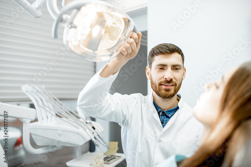 Dentist preparing for the medical examination with young woman patient in the dental office