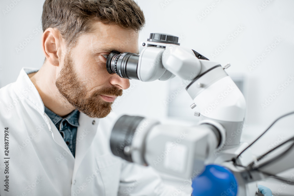 Male dentist examining patient with a professional microscope at the dental office