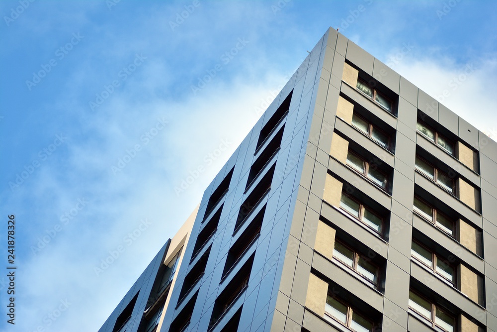 New block of modern apartments with balconies and blue sky in the background