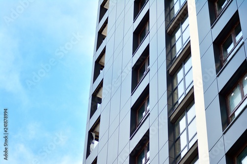 New block of modern apartments with balconies and blue sky in the background