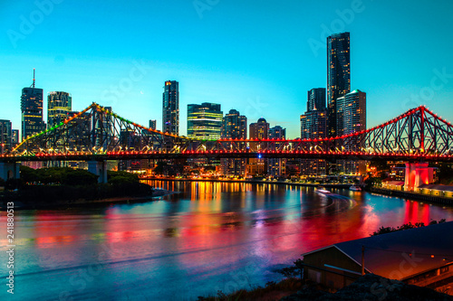Colourful skyline of Brisbane by night with illuminated Story Bridge and clear blue sky (Brisbane, Queensland, Australia)