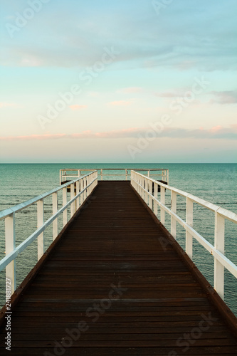 Close-up of wooden pier during sunset overseeing the ocean with orange clouds and turquoise sky  Hervey Bay near Fraser Island  Queensland  Australia 