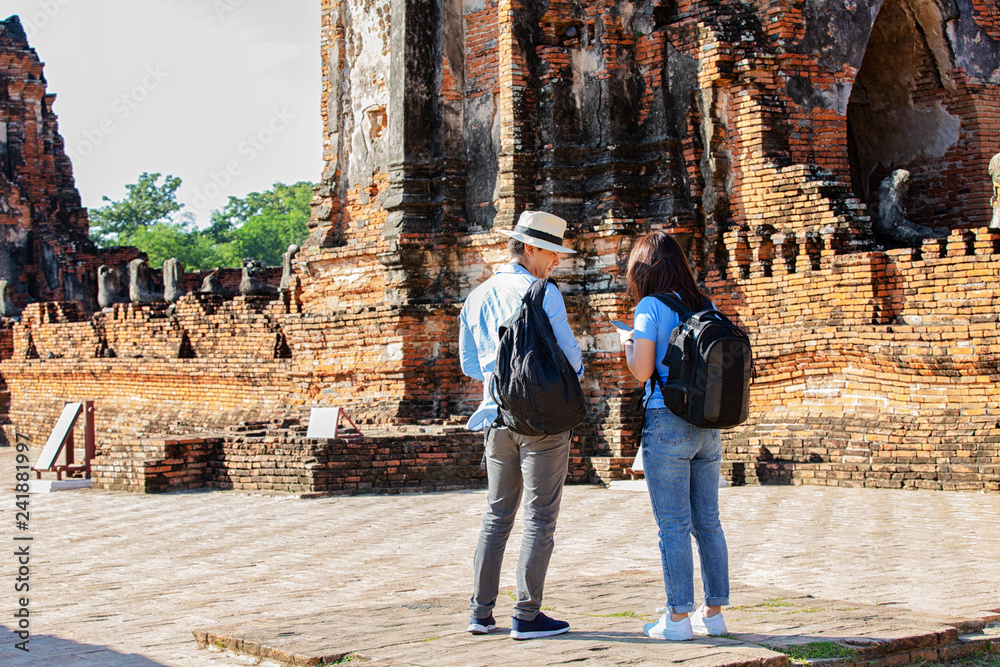 Eastern Asia summer holidays. Caucasian man and Asian woman tourist from back looking at Wat Chaiwatthanaram temple. Tourist travel in the morning at temple in old city of Ayutthaya in Thailand.