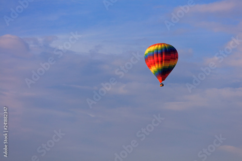 Flight of a beautiful multi-colored and motley balloon in the blue sky.