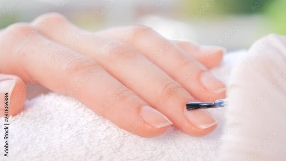 Beautician doing manicure with nail varnish.