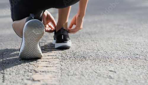 A young woman stopped to tie a string while running in the stadium  Fitness woman runner tying shoelace before running 