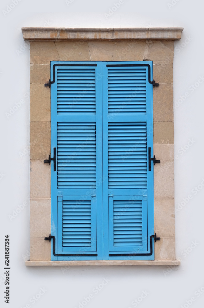 View of neat blue window with closed striped shutters in stone frame front view