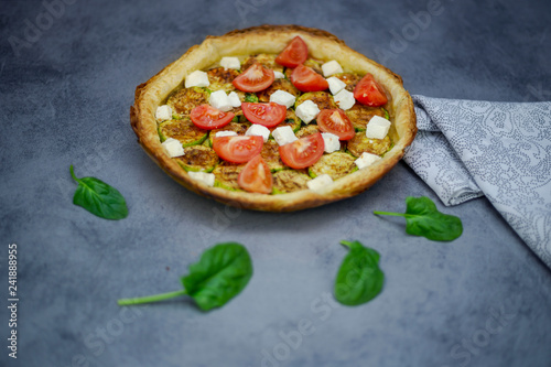 Homemade tart with grilled zucchini, tomatoes, goat's cheese and spinach