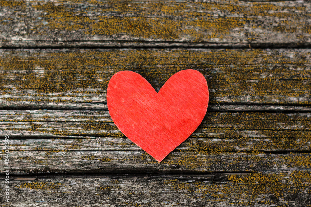 Red wooden heart on an old weathered wooden surface with cracks background Red wooden heart on an old weathered wooden surface with cracks background