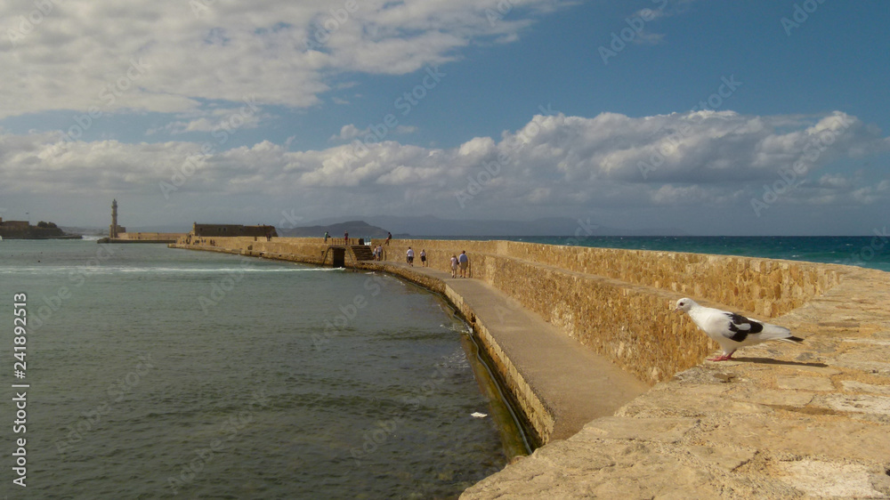 A yellow brick wall leads to the lighthouse and protects the city from the waves and invaders, Chania
