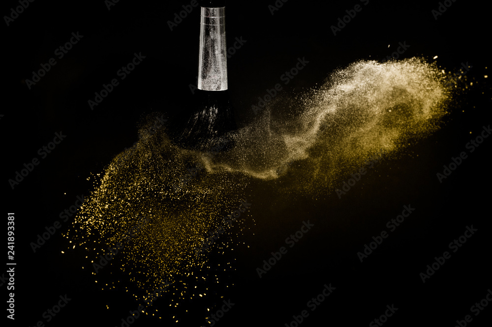 Obraz premium Cosmetic brush with golden cosmetic powder spreading for makeup artist in black background, look like a luxury mood.