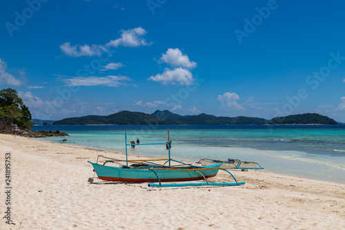 Tropical background view from Malcapuya island with traditional philippines boat and white sand beach. Travel vacation at Philippines.