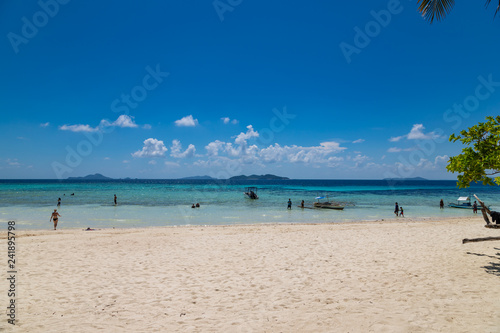 PALAWAN / PHILIPPINES - NOVEMBER 01, 2018: Tropical background view from Malcapuya island with traditional philippines boats and swimming tourists. Travel vacation at Philippines.