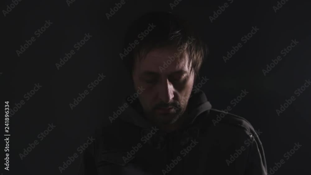 Man feeling guilt and remorse, low key portrait of sad adult caucasian male in dark interior