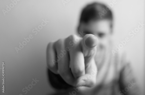 Teen boy out of focus points with index finger in front of him photo