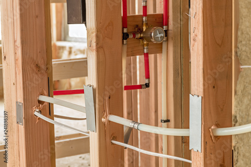 Water pipes pass through wooden studs in new home construction photo