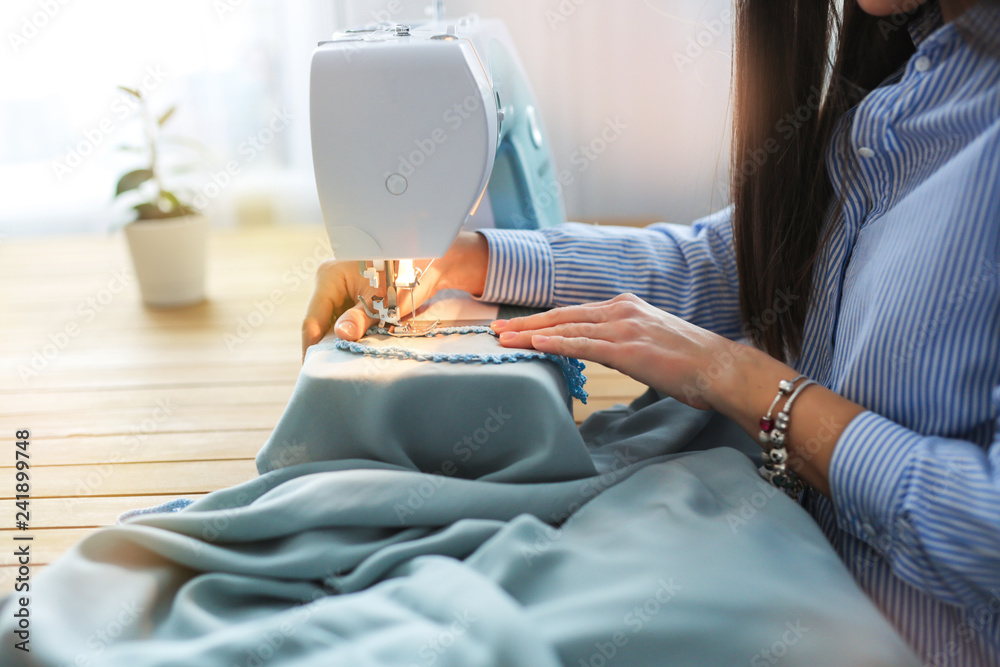woman sews on sewing machine in real room