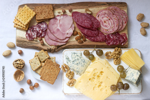 Appetizer of various types of sausages, meats, cheeses and crackers on a wooden board, served to wine.
