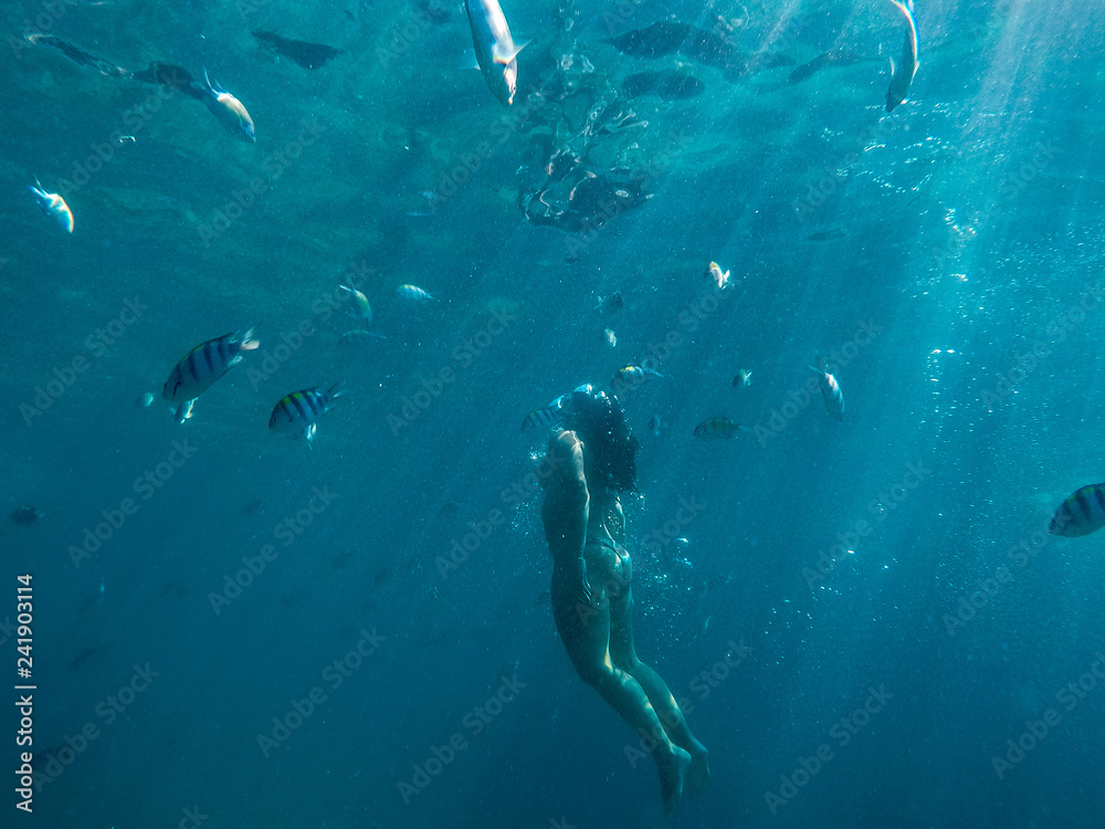 Woman swimming underwater on a blue sea and clear water with good visibility for snorkeling.
