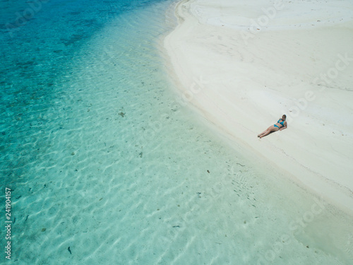 AERIAL: Girl in bikini lying on the sandy beach and suntanning in Cook Islands.