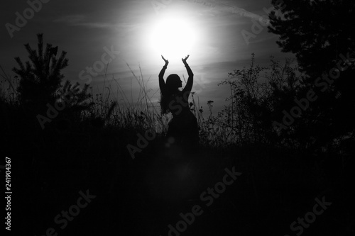 Silhouette of dancing woman on a meadow during beautiful summer sunset