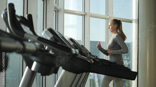 Attractive woman of middle age is running on tread mill in sport gym photo