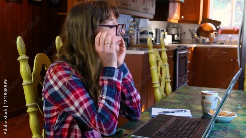 Woman at the table working with laptop. Girl with glasses and wearing a checkered shirt is typing on her keyboard then gets discouraged and removes her glasses. Travelling up Woman at the table working with laptop. Girl with glasses and wearing a checkered shirt is typing on her keyboard then gets discouraged and removes her glasses. Travelling up