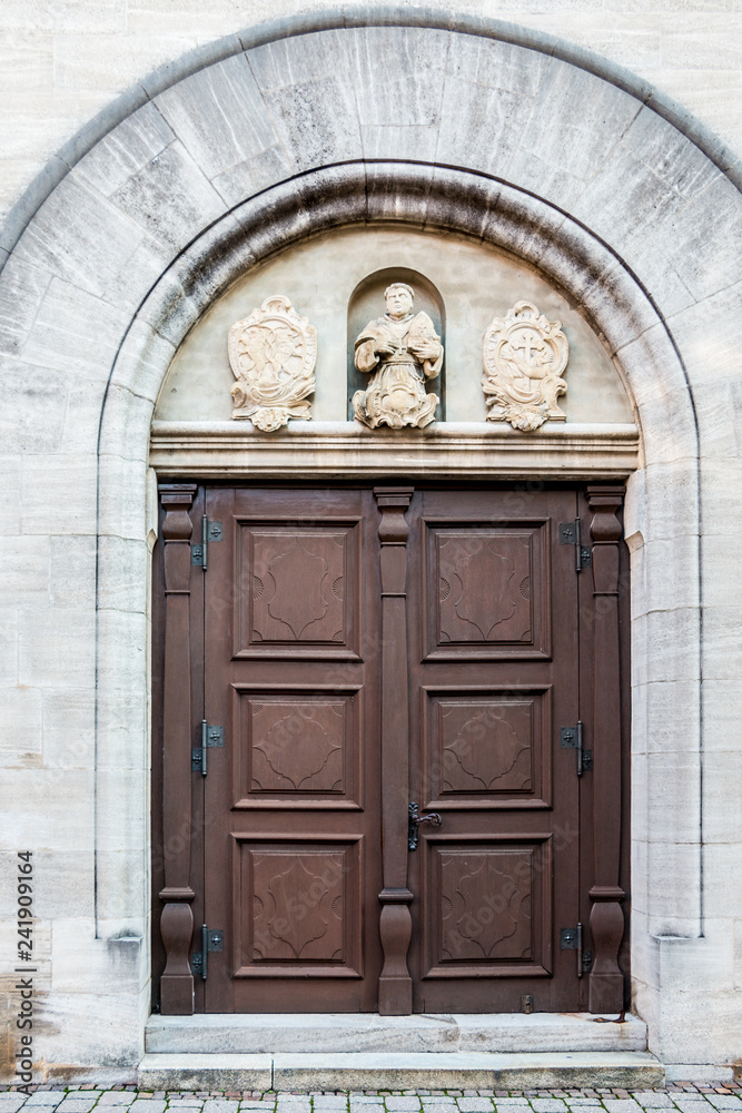 Old door of a historical building with statues and coats of arms made of stone Old door of a historical building with statues and coats of arms made of stone