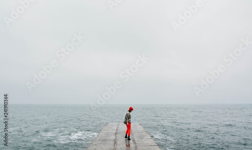 Woman walking on the empty beach in winter time. Art photo with added film and grain filter