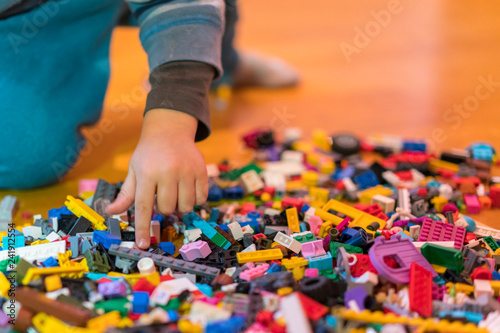 Close up of colorful plastic bricks on the floor. Early learning. Children s plastic constructor on the floor. Children s hands play a little constructor. vertical photo.