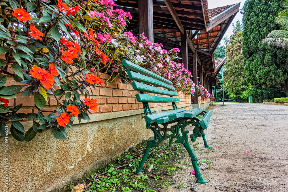 Wooden bench in front of the brick wall with flowers