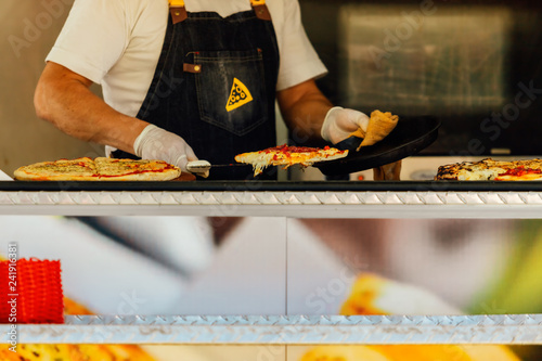 Pizza man serves pizza with a spatula on the counter of a food truck
