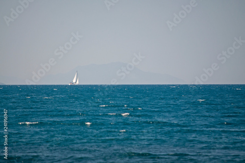 Sailboat in the sea in the evening sunlight over beautiful big mountains background, luxury summer adventure, active vacation in Mediterranean sea, Turkey Marmaris