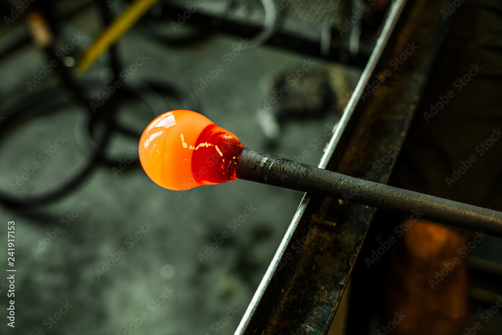 Man is making a blown glass lantern. Man is starting a glass blowing project to create an ocher colored lantern. Close up shot on his stick Man is making a blown glass lantern. Man is starting a glass blowing project to create an ocher colored lantern. Close up shot on his stick