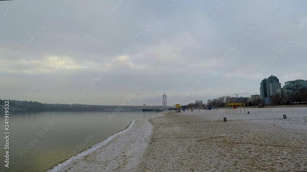 the camera smoothly moves away from the riverbank where the snow flakes fall and melt the camera smoothly moves away from the riverbank where the snow flakes fall and melt