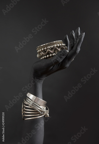 Black woman's hand with Silver jewelry. Oriental Bracelets on a black painted hand. Silver Jewelry