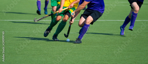 Fototapeta Naklejka Na Ścianę i Meble -  Close up of two field hockey players, challenging eachother for the control and posession of the ball during an intense, competitive match on professional level