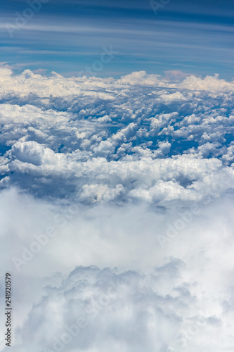 Beautiful view from window of plane flying over clouds. Natural panorama with clouds. White clouds moving above the ground. 