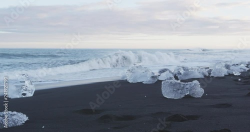 Photographer taking photos in nature on Iceland Diamond Beach with Ice. Woman photographing at okulsarlon Iceberg beach aka Breidamerkursandur on South coast of Iceland. RED EPIC SLOW MOTION photo