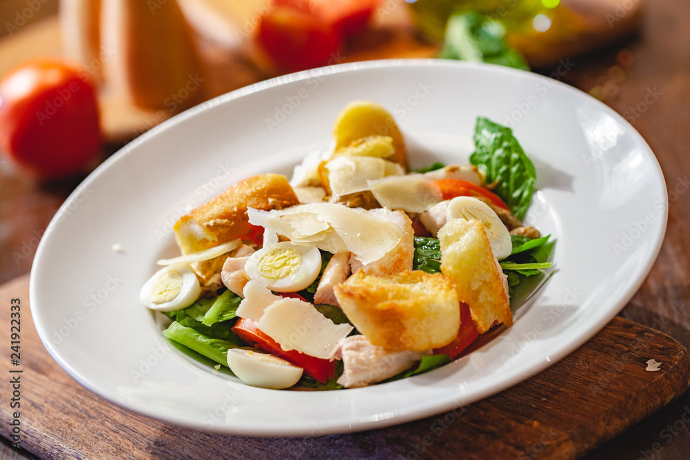 Caesar salad with chicken breast, eggs, croutons, parmesan cheese on white plate. Close up Caesar salad with chicken breast, eggs, croutons, parmesan cheese on white plate. Close up