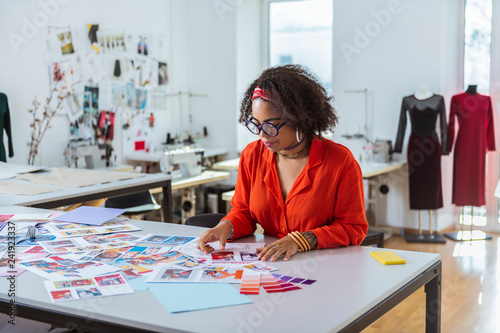 Concentrated young female with short curly hair dealing with sketches