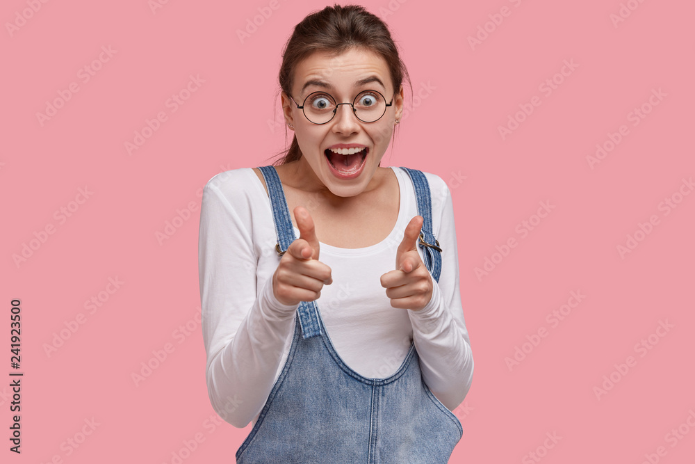 Photo of happy woman points with both fingers at camera, has cheerful expression, smiles excitedly, says: Its your chance, poses against pink background. You are what we need. Girl meets you Photo of happy woman points with both fingers at camera, has cheerful expression, smiles excitedly, says: Its your chance, poses against pink background. You are what we need. Girl meets you