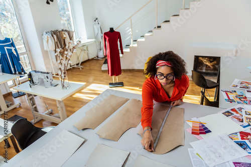 Accurate attentive lady measuring paper models of her future creation