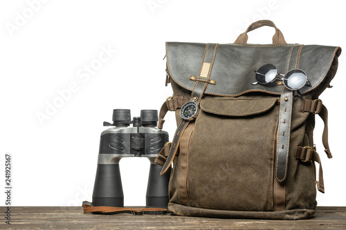 Vintage brown backpack with tourism accessories on a table with an isolated background.