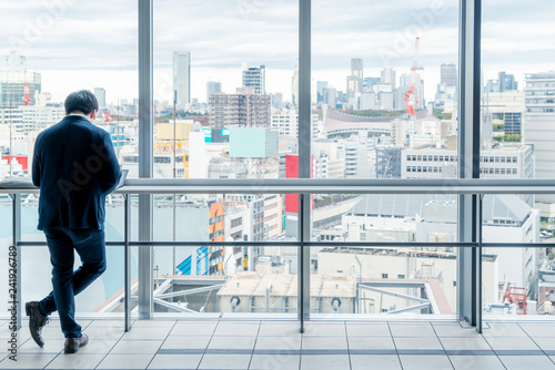 Asia Business concept for real estate and corporate construction - Asia businessman stand on window in high office with city skyline in Tokyo  Japan