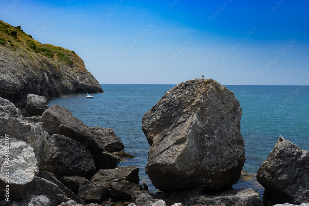 Seascape with a rocky shore line under a blue sky.