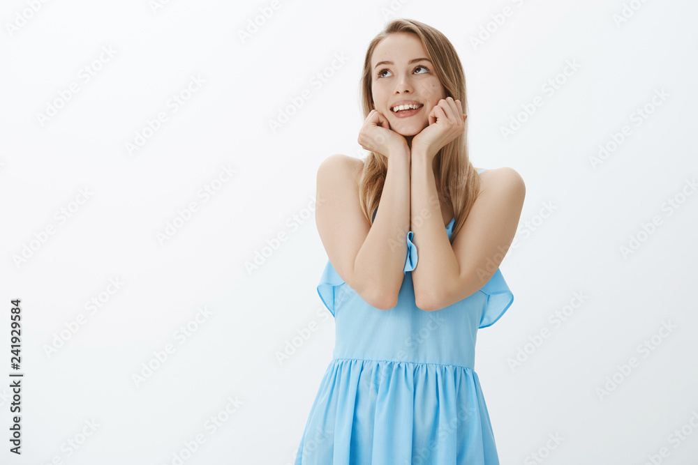 Sweet and gentle romantic young girlfriend with blond hair and cute moles leaning head on palms sighing from love and sympathy gazing at upper left corner nostalgic, posing in blue dress Sweet and gentle romantic young girlfriend with blond hair and cute moles leaning head on palms sighing from love and sympathy gazing at upper left corner nostalgic, posing in blue dress