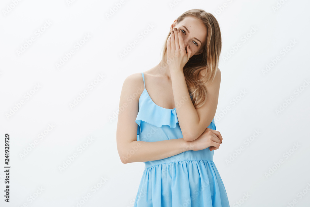 Funny enthusiastic girl chuckling, laughing over brother tilting head covering mouth with palm having fun and fooling around, wearing elegant blue dress posing amused against grey wall Funny enthusiastic girl chuckling, laughing over brother tilting head covering mouth with palm having fun and fooling around, wearing elegant blue dress posing amused against grey wall