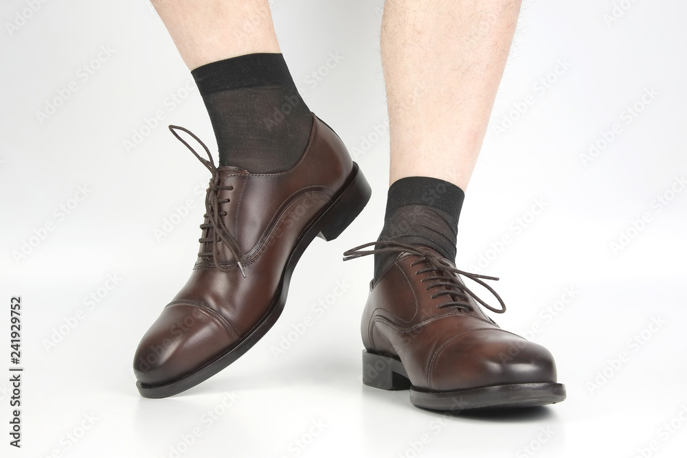 Male legs in socks and brown classic shoes on a white background Male legs in socks and brown classic shoes on a white background