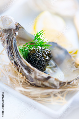 Fresh oysters with black caviar. Opened oysters with black sturgeon caviar. Gourmet food. Delicatessen. Vertical image